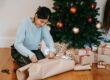 femme qui emballe des cadeaux de Noël à côté du sapin