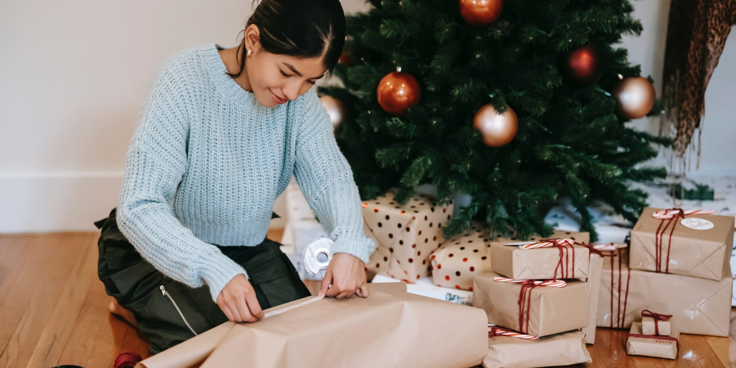 cadeau-noel femme qui emballe des cadeaux de Noël à côté du sapin