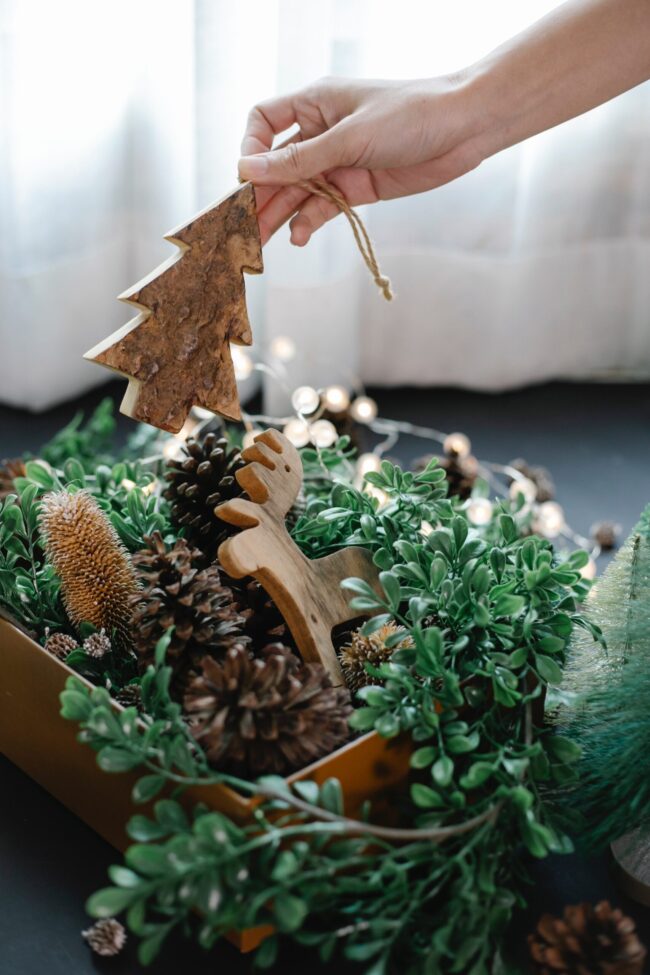 pexels-laura-james-6102212 Décorations de Noël composée de petits sapin en bois, pomme de pin et guirlandes