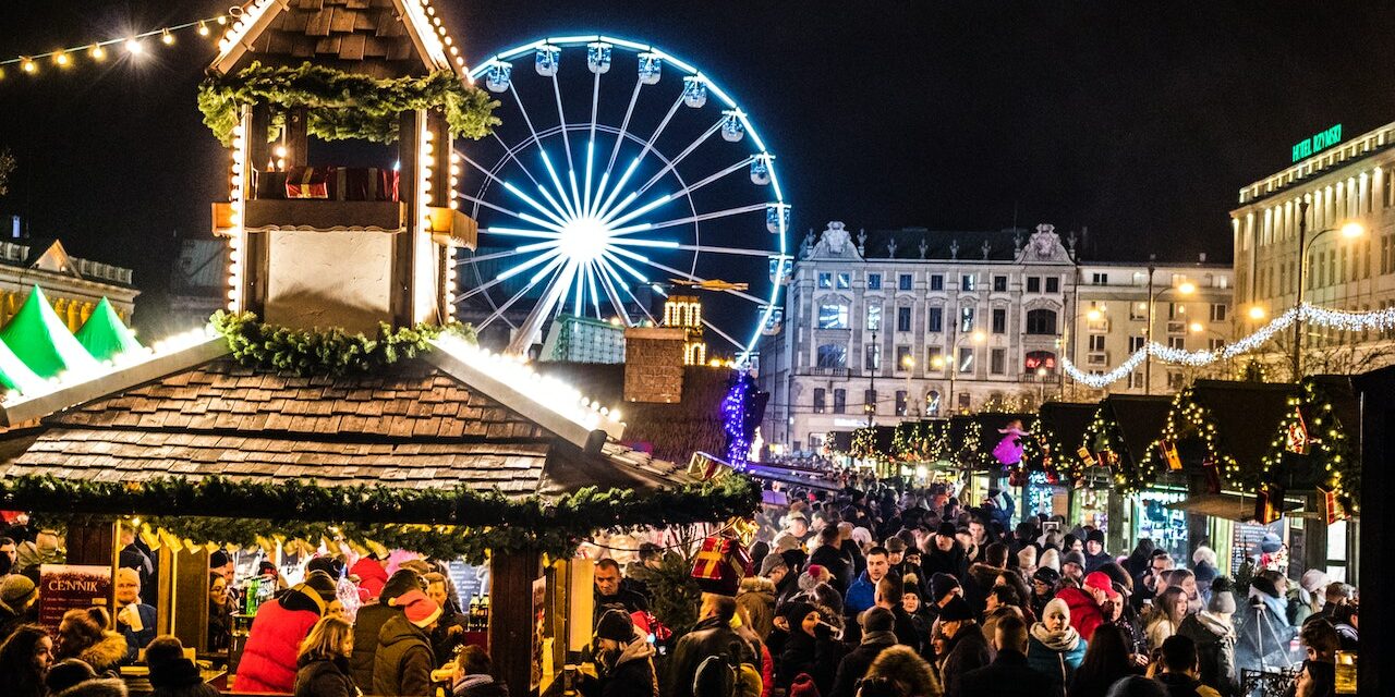 Marché de Noël illuminé Marché de Noël rempli de monde et illuminé de guirlande et décoration de Noël. Grande roue visible en arrière plan.