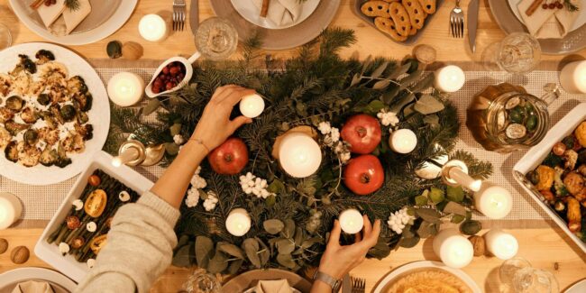 Jolie table dressée pour Noël et décorée avec des bougies et branches de sapin.